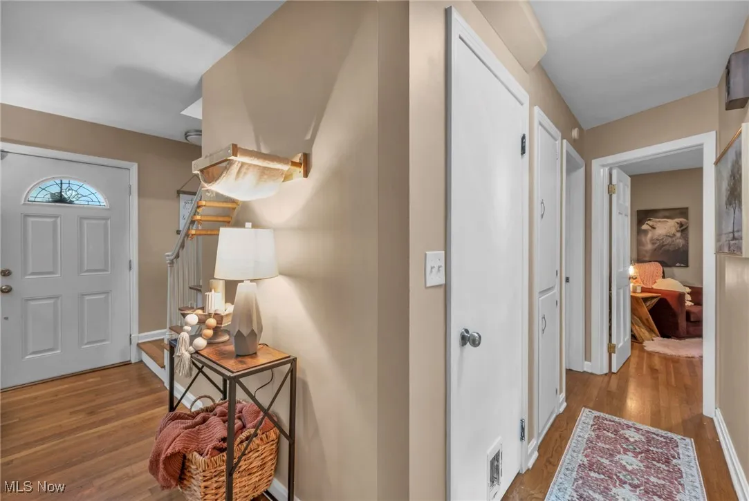 Hallway from kitchen view showing front door and hallway with 2 cupboards for storage and entrance to basement, bathroom and 2 bedrooms.