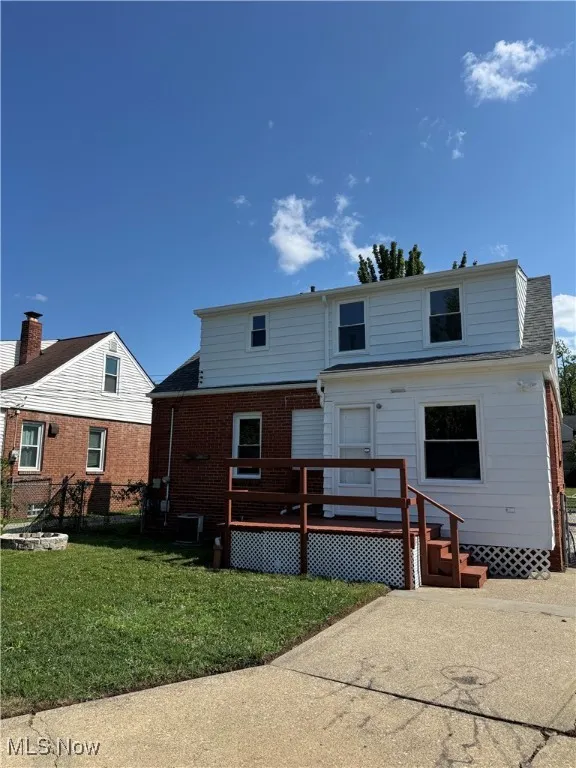 Back of property with a deck, a yard, and brick siding