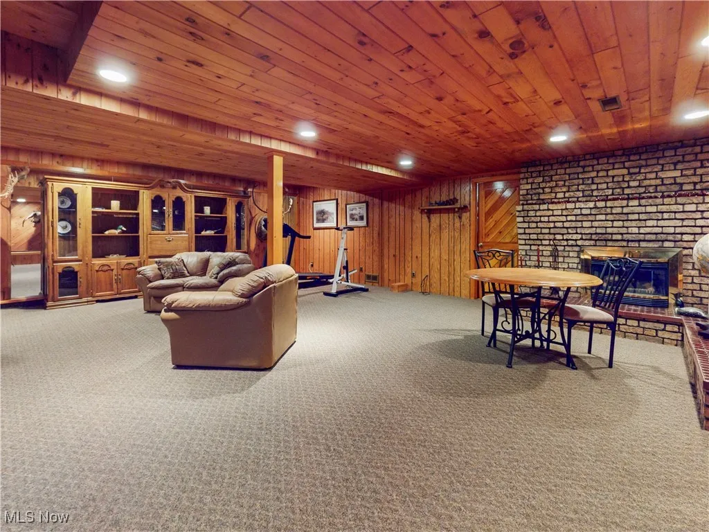 Carpeted living room featuring recessed lighting, a fireplace, wood ceiling, and wooden walls