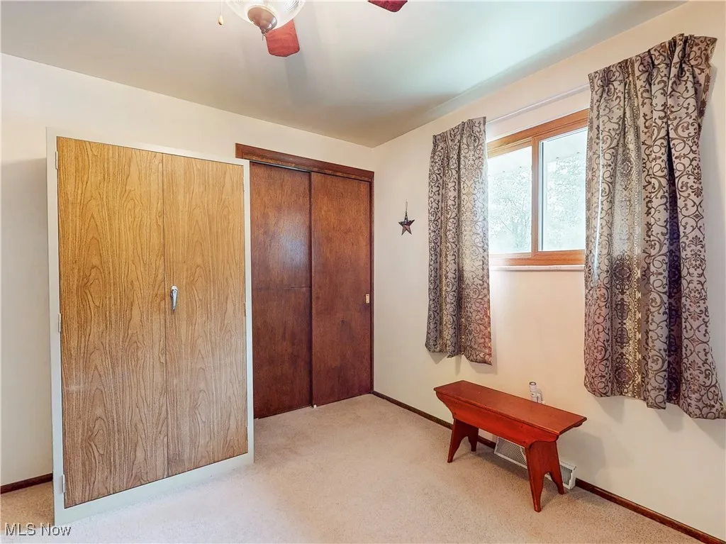 Bedroom featuring light colored carpet, a closet, and a ceiling fan