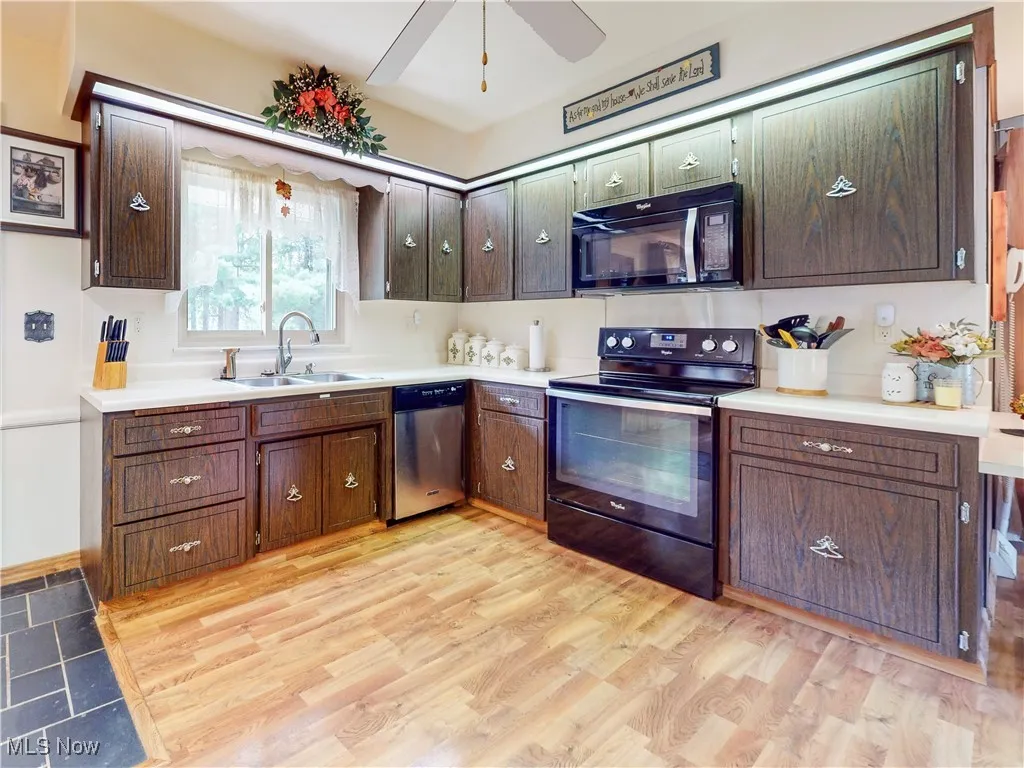 Kitchen with black appliances, light countertops, a ceiling fan, light wood-style floors, and dark brown cabinets
