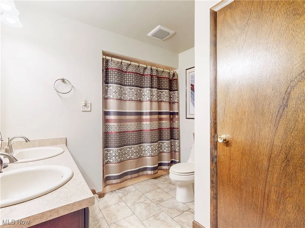 Bathroom featuring double vanity and curtained shower