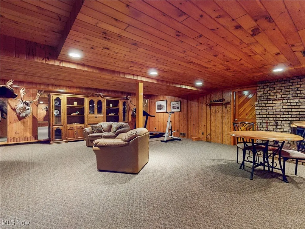 Living room featuring recessed lighting, carpet, wood walls, and wood ceiling