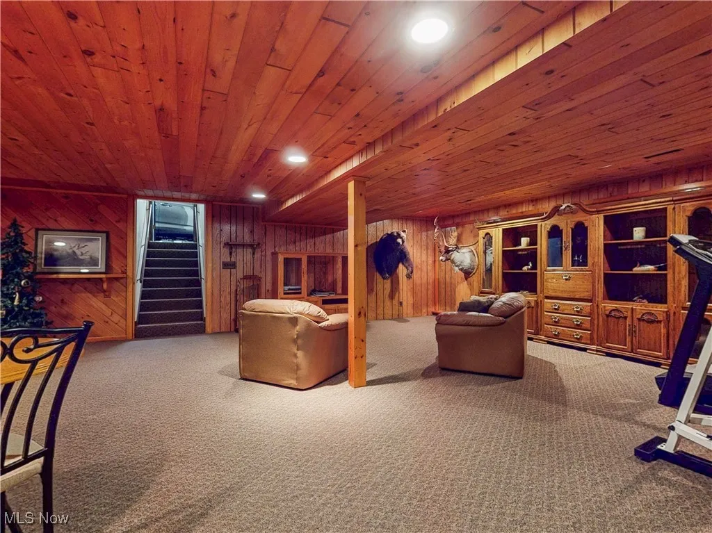 Carpeted living room featuring stairway, recessed lighting, wood walls, and wood ceiling