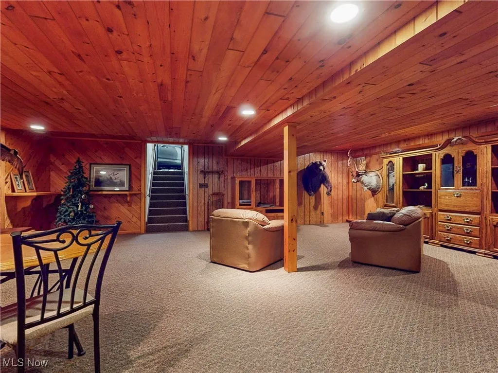 Living area with recessed lighting, stairs, carpet floors, wooden walls, and wood ceiling
