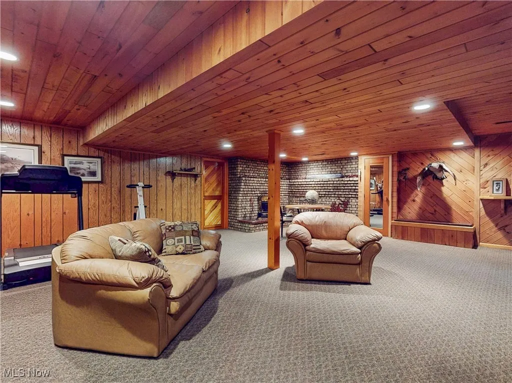 Living room featuring recessed lighting, wood walls, wooden ceiling, and carpet