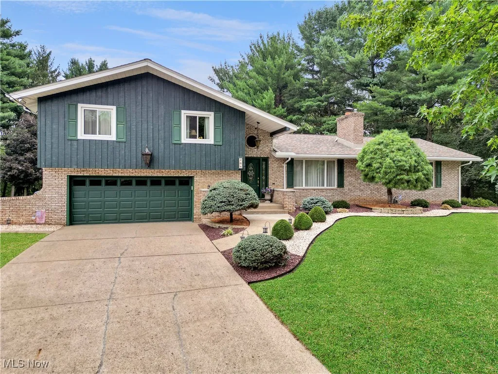 Split level home with an attached garage, a front yard, driveway, and brick siding