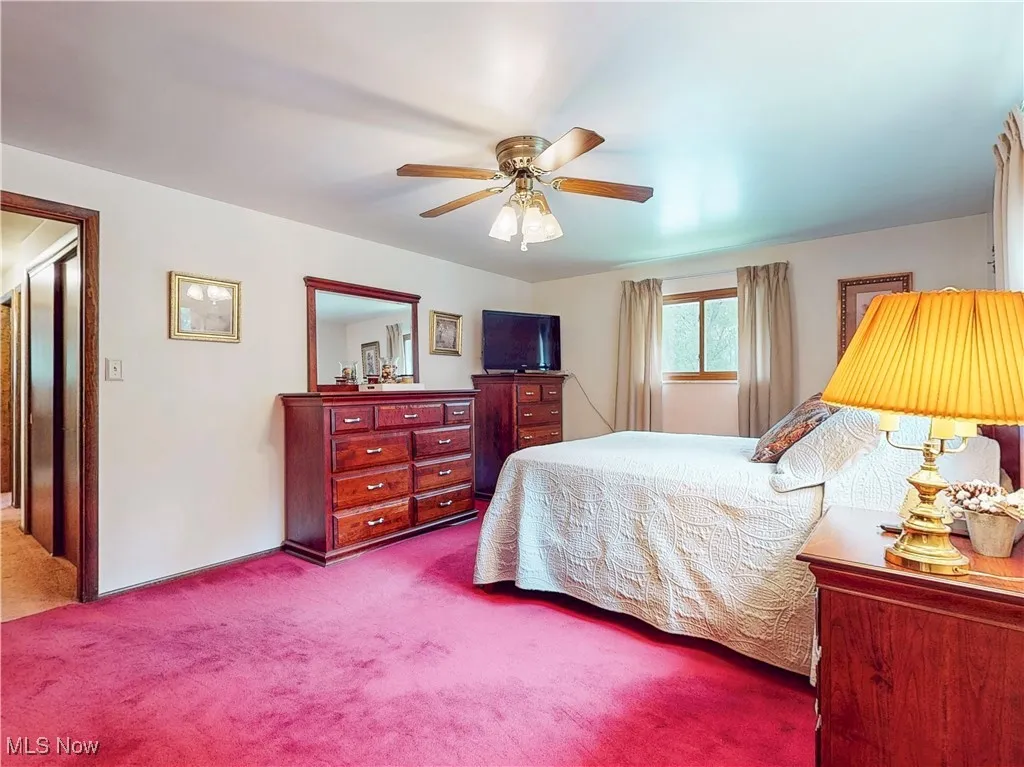 Carpeted bedroom with a ceiling fan and baseboards