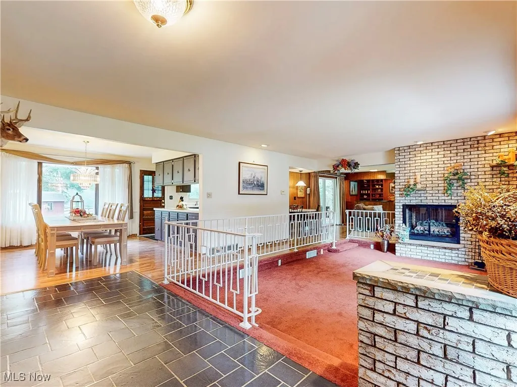 Living room with a brick fireplace, dark colored carpet, and dark stone finish flooring
