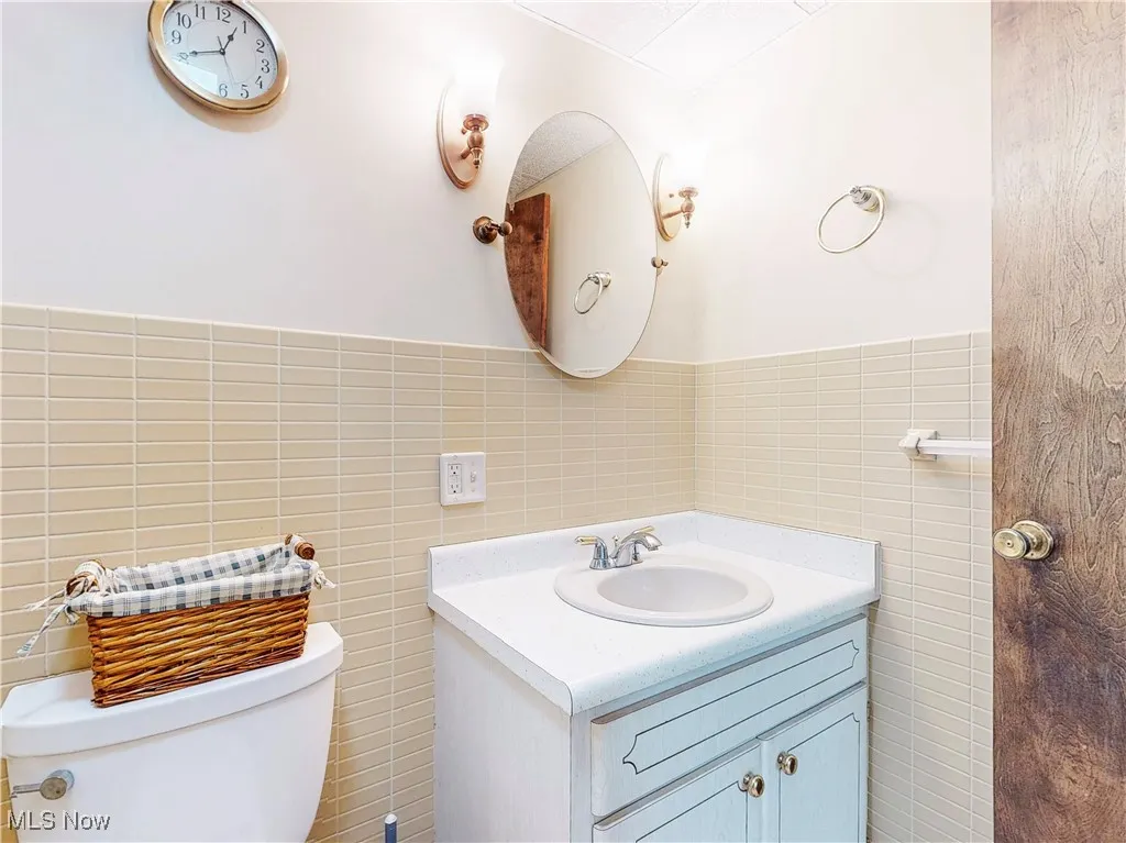 Bathroom featuring vanity, tile walls, and wainscoting