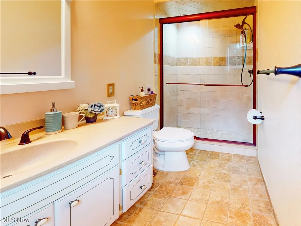 Full bath with vanity, a shower stall, and tile patterned floors