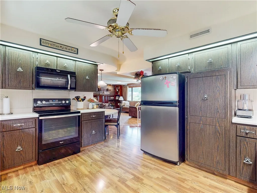 Kitchen with black appliances, light countertops, light wood-style floors, and a ceiling fan