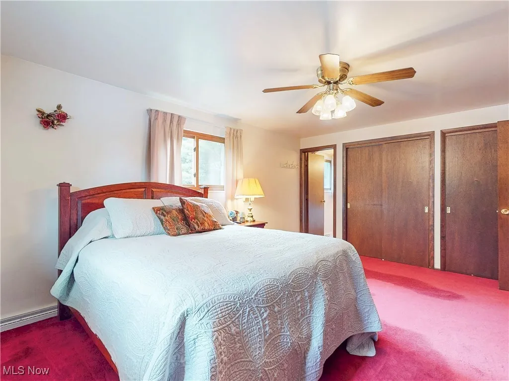 Carpeted bedroom with two closets and a ceiling fan