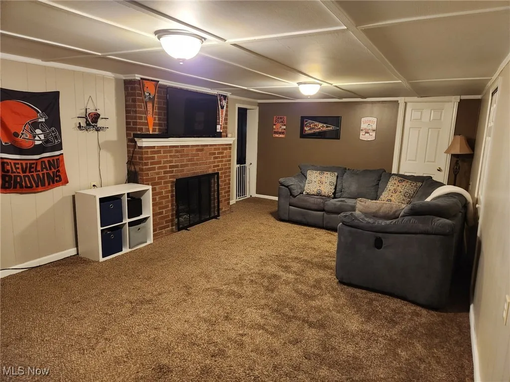 Bsmnt. family room with a brick wwod burning fireplace and carpet flooring (side view).