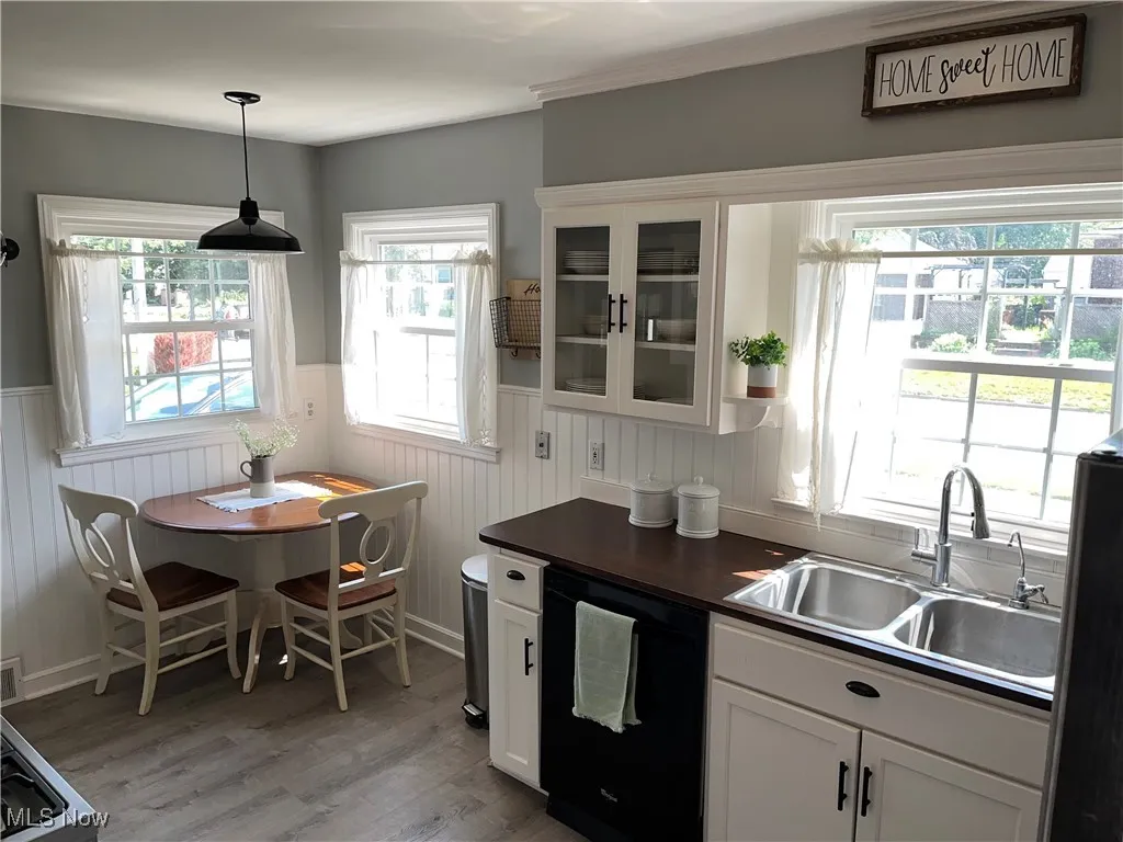 Kitchen with black dishwasher, light wood-style floors, white cabinets.