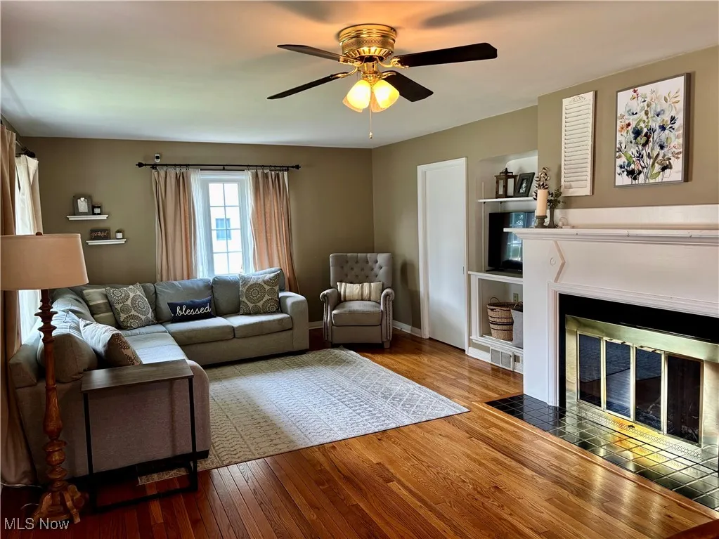 Living room featuring hardwood / wood-style flooring, ceiling fan, and a glass covered fireplace