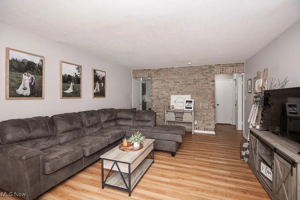 Living area with light wood-type flooring and brick wall