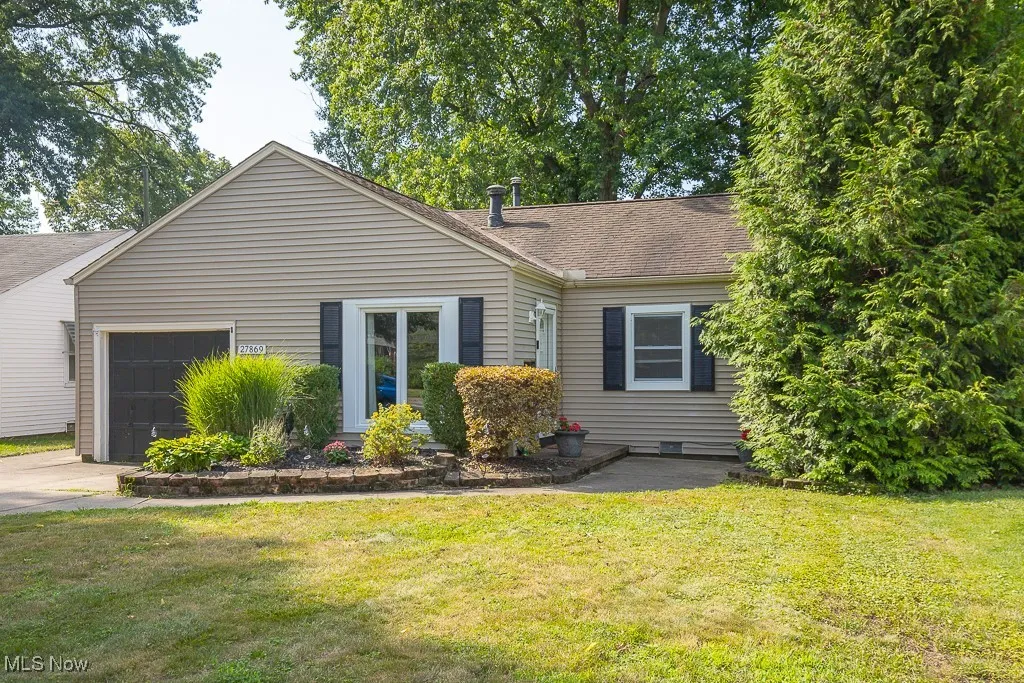 View of front of property with a garage, a shingled roof, a front yard, and driveway