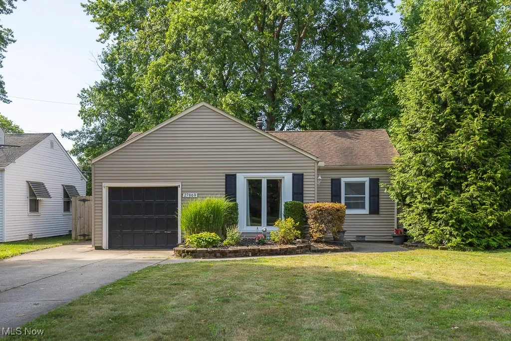 View of front of property with concrete driveway, roof with shingles, a front yard, and a garage
