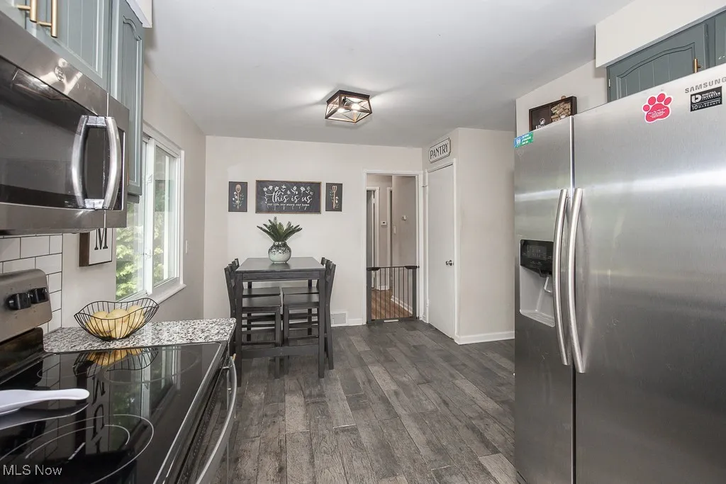 Kitchen with stainless steel appliances, dark wood-type flooring, and backsplash