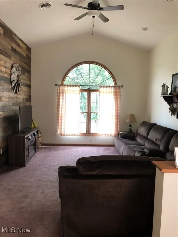 Carpeted living area with vaulted ceiling and ceiling fan