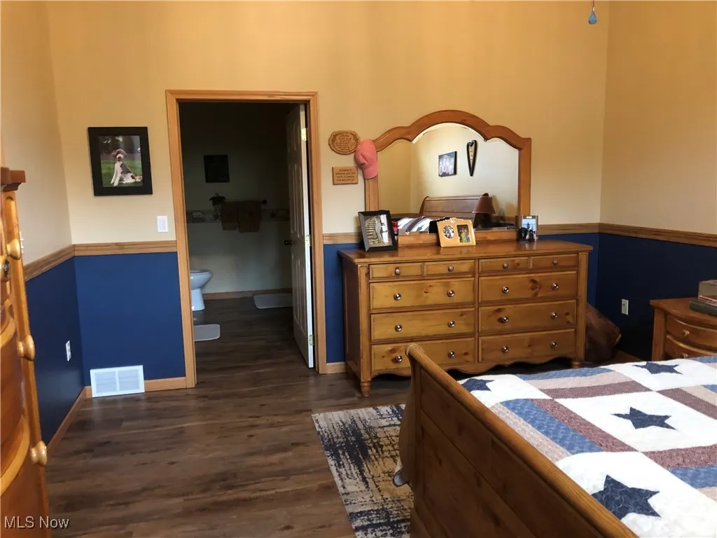 Bedroom with dark wood-type flooring and ensuite bath