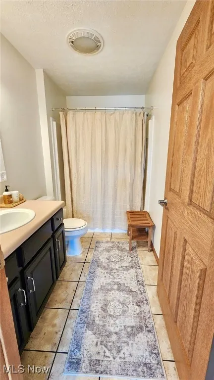 Full bathroom with vanity, tile patterned floors, a textured ceiling, and a shower with shower curtain