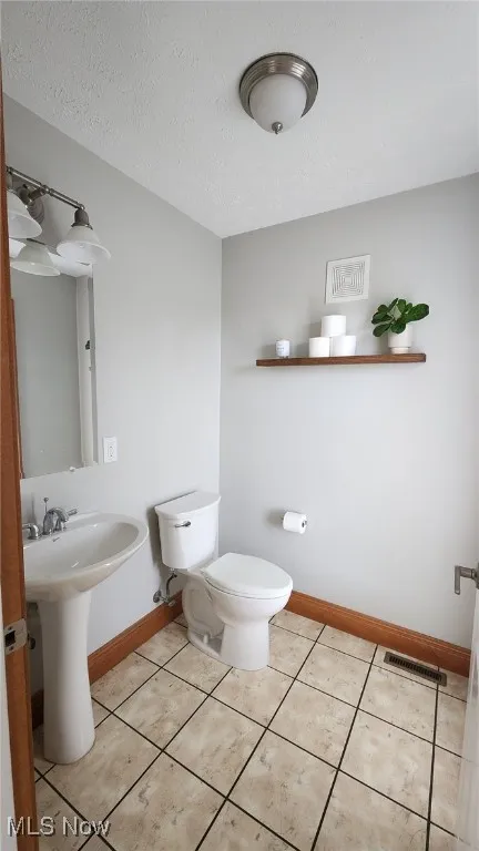 Half bathroom featuring a textured ceiling and tile patterned flooring