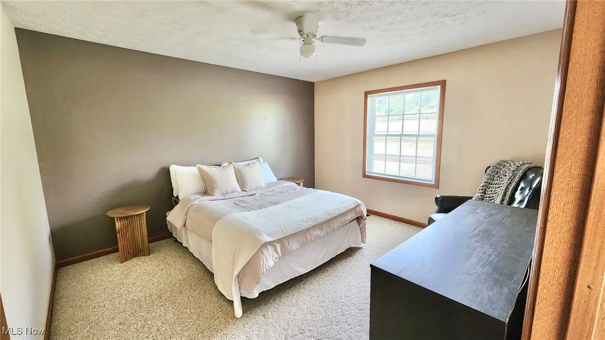 Bedroom featuring light carpet, a textured ceiling, and ceiling fan