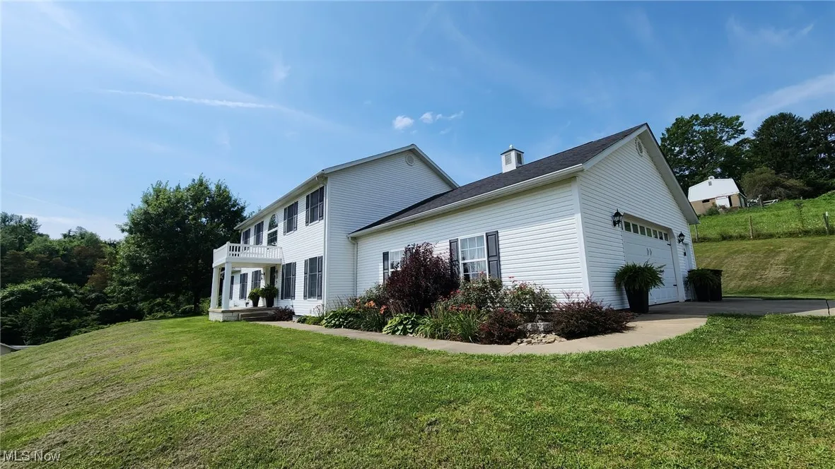 View of property exterior with a yard, a garage, asphalt driveway, and a balcony