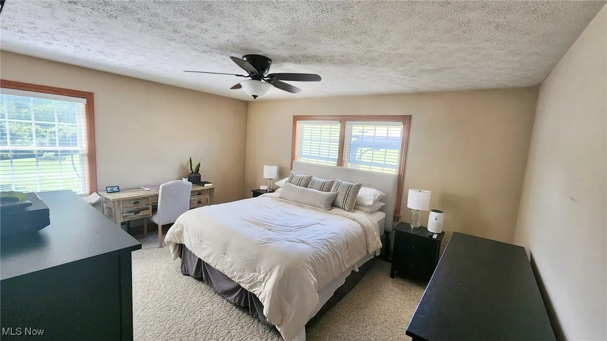 Bedroom featuring a textured ceiling, a ceiling fan, and light colored carpet