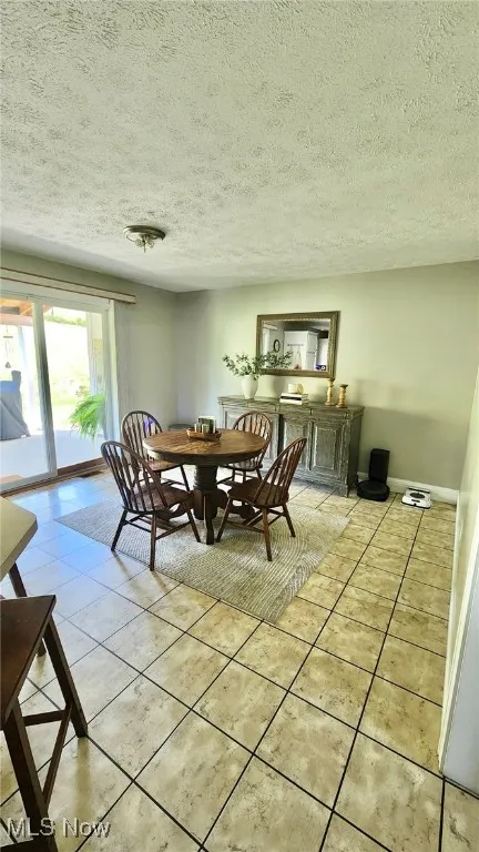 Dining area featuring light tile patterned floors and a textured ceiling