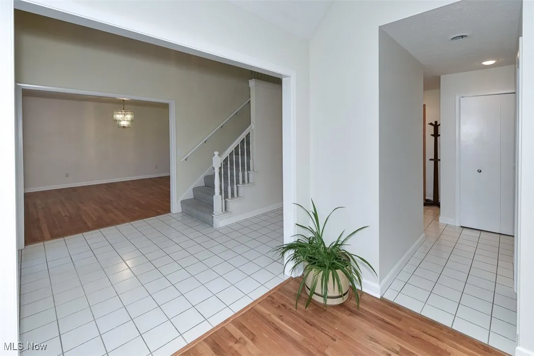 Spare room with light tile patterned floors, a chandelier, and stairway