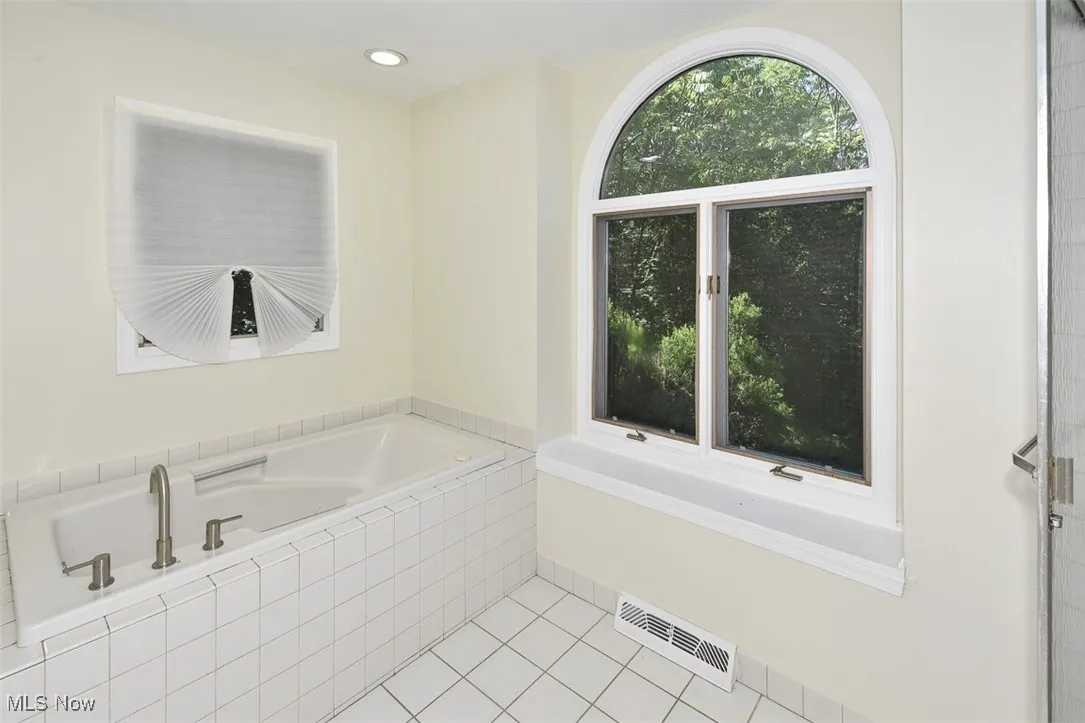 Bathroom with a bath, tile patterned flooring, and recessed lighting