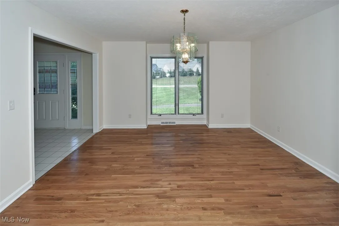 Unfurnished dining area featuring a chandelier, a textured ceiling, and wood finished floors