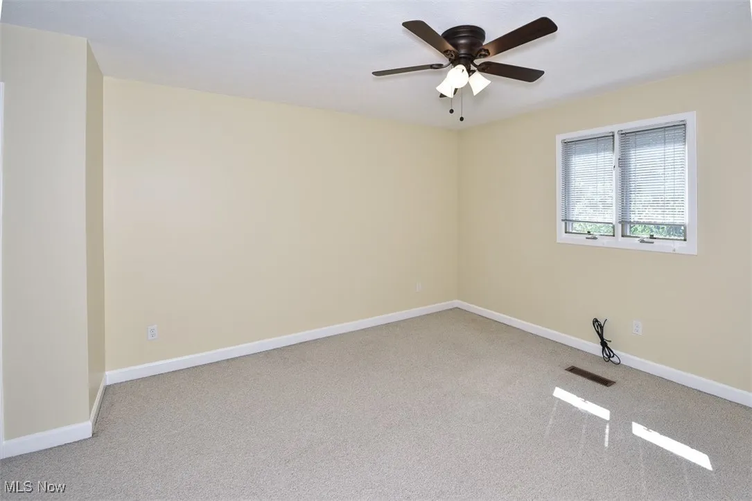 Carpeted spare room with baseboards and a ceiling fan