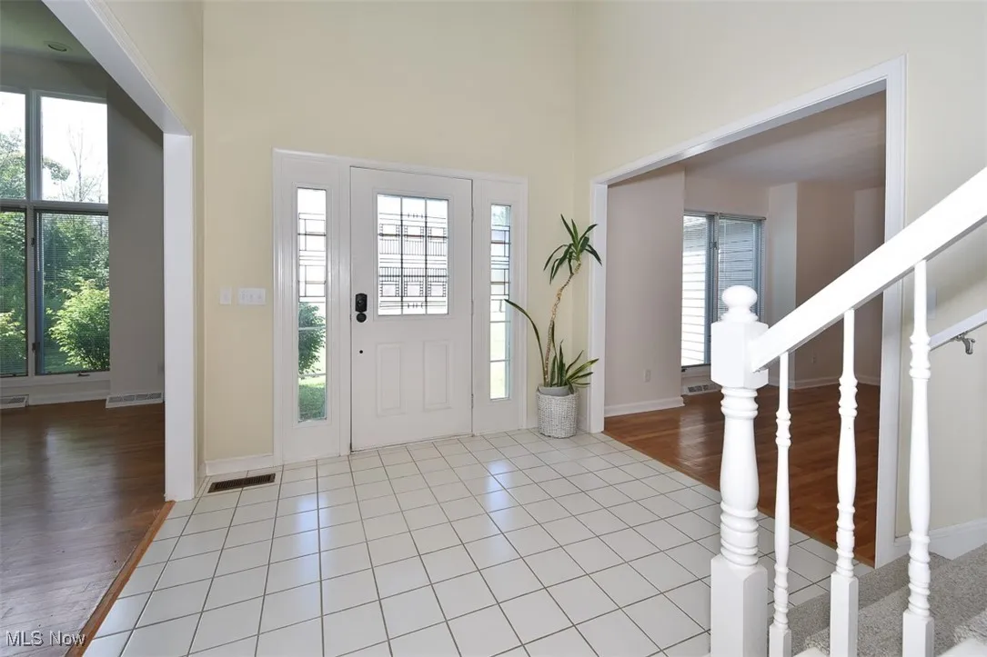 Foyer with stairway, light wood-type flooring, and a high ceiling
