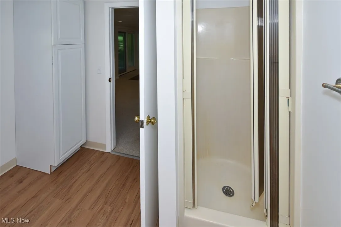 Full bath featuring wood finished floors and a shower stall