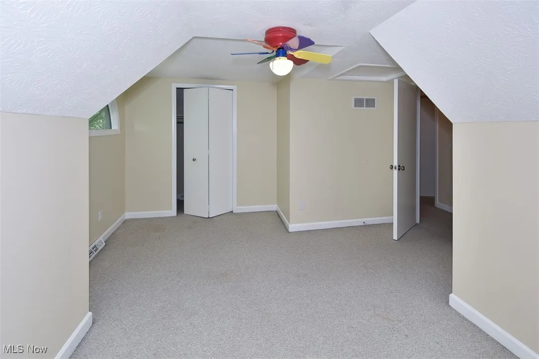 Bonus room with a textured ceiling, carpet, and vaulted ceiling