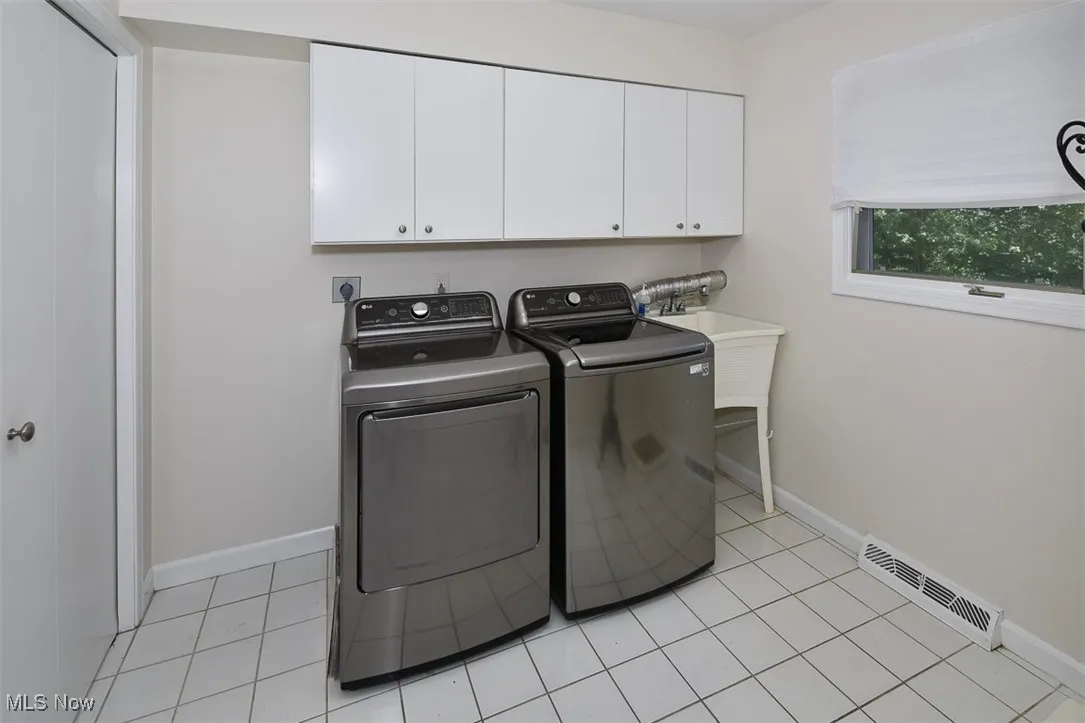 Laundry area featuring cabinet space, washing machine and clothes dryer, and light tile patterned floors