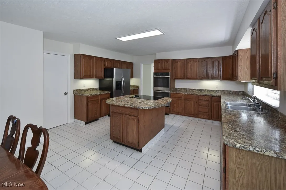 Kitchen featuring light tile patterned floors, a kitchen island, and stainless steel appliances