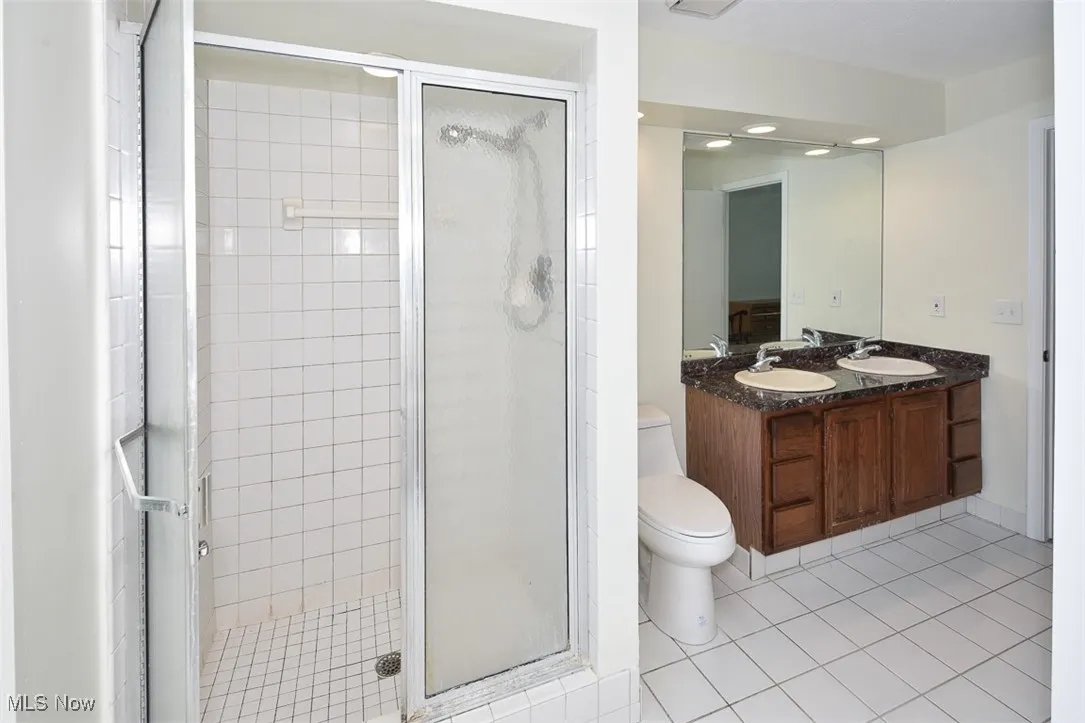 Bathroom featuring a shower stall, tile patterned floors, and double vanity