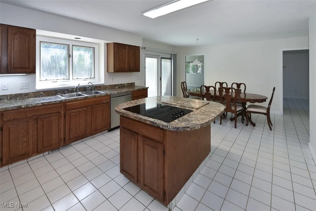 Kitchen featuring plenty of natural light, light tile patterned floors, a kitchen island, and dark countertops