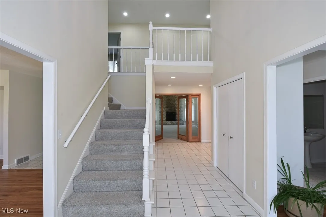 Stairs featuring a high ceiling, recessed lighting, and tile patterned floors