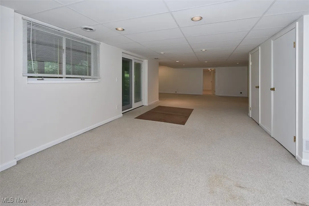 Carpeted empty room with a drop ceiling and recessed lighting