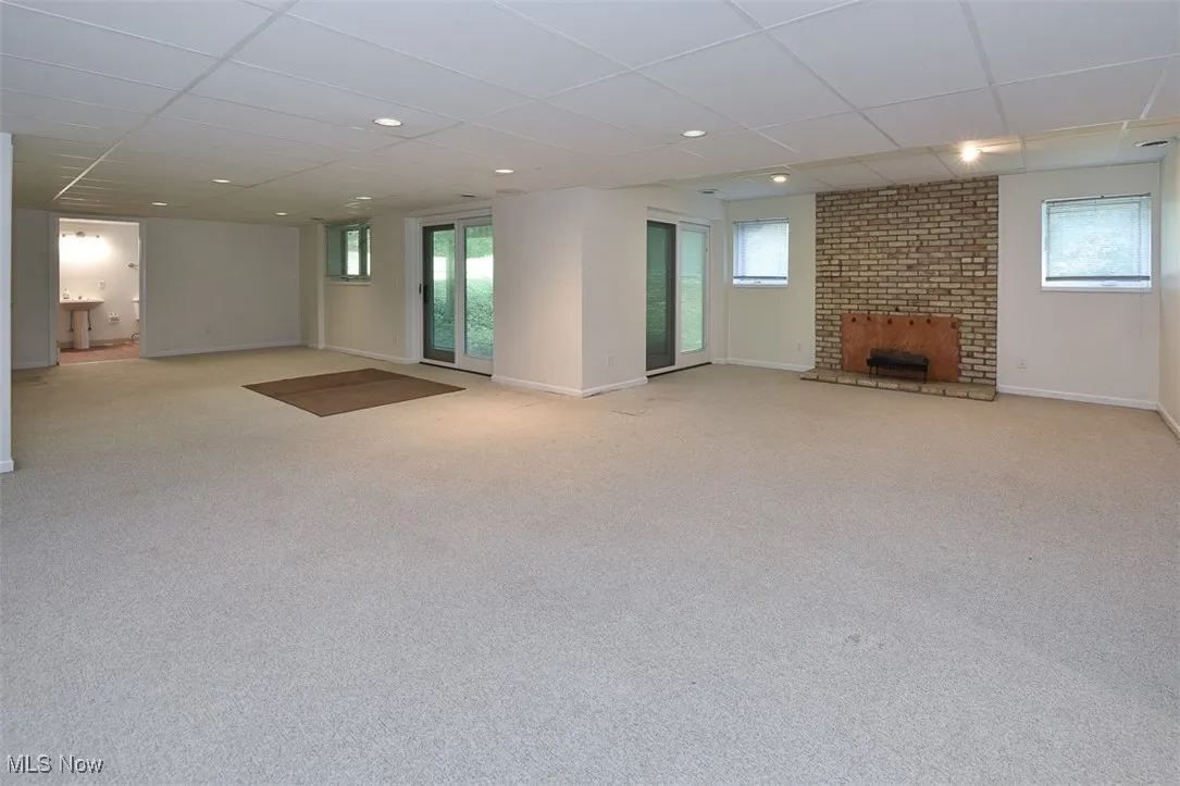 Below grade area with a drop ceiling, light carpet, a fireplace, healthy amount of natural light, and recessed lighting