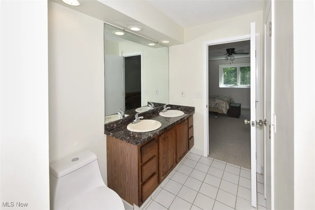 Bathroom featuring double vanity, ensuite bathroom, tile patterned flooring, and a ceiling fan