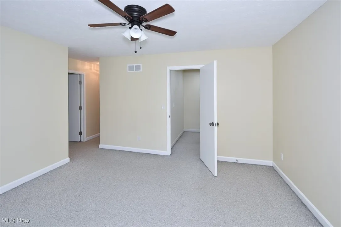 Empty room with light carpet and a ceiling fan