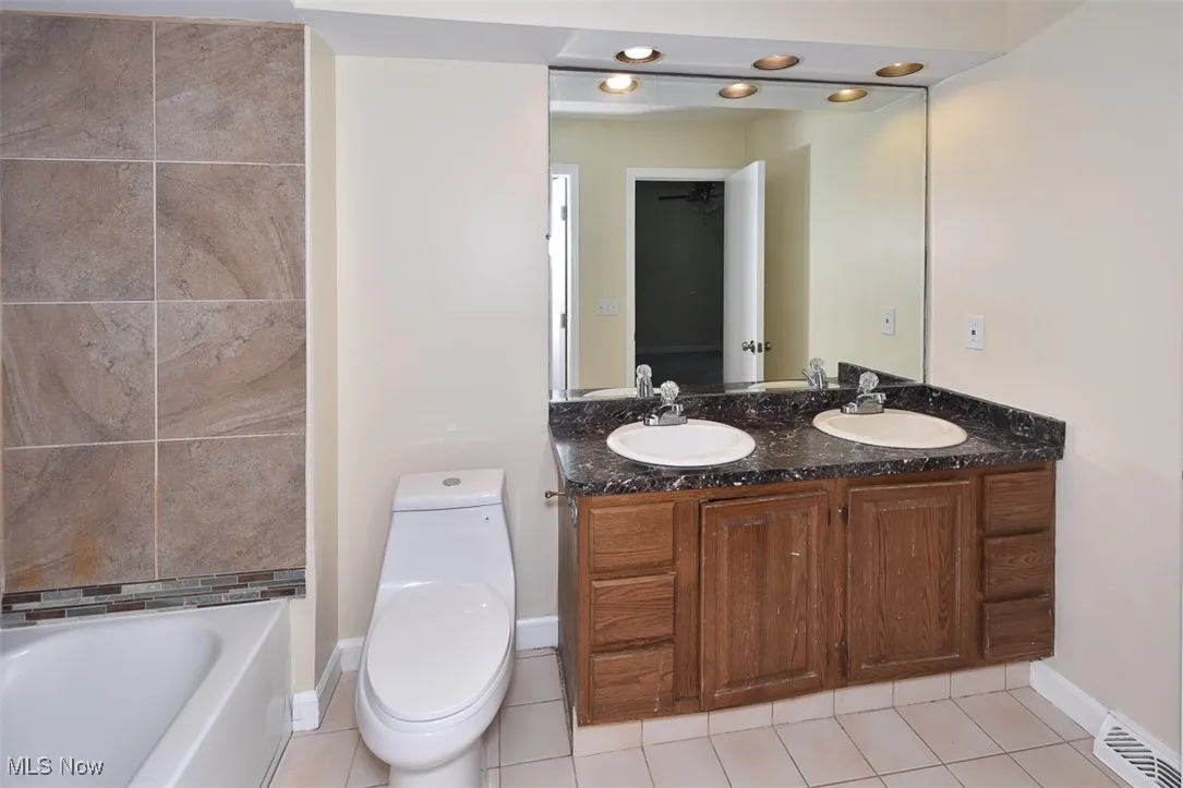 Full bath with tile patterned floors and double vanity