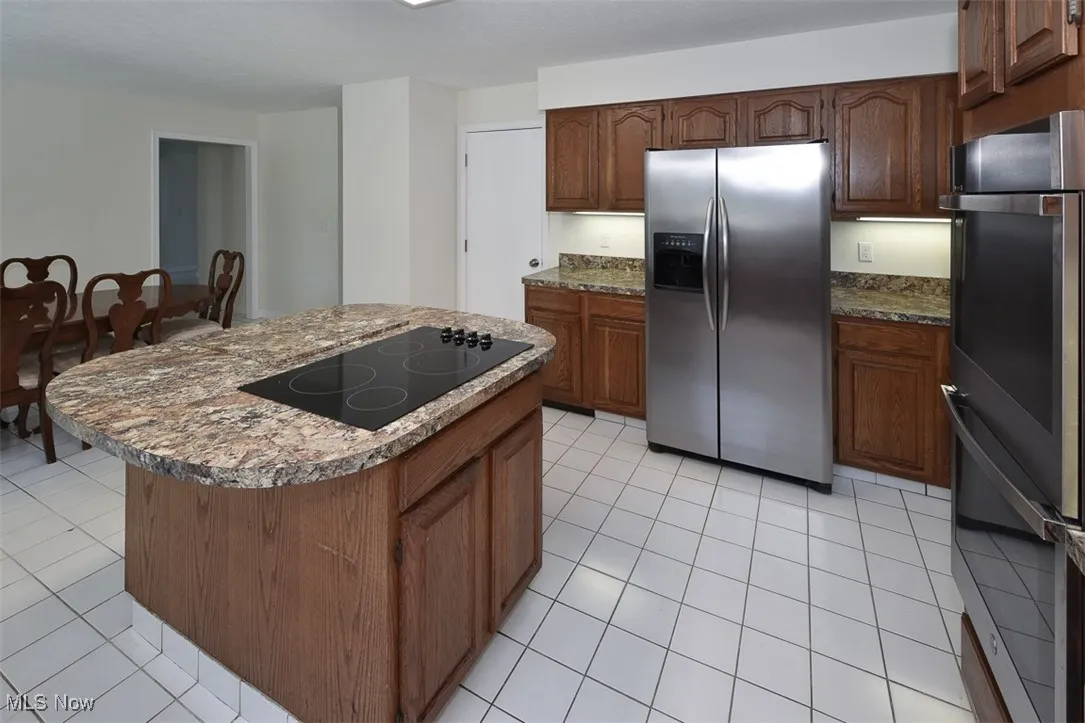 Kitchen with stainless steel appliances, light tile patterned flooring, and a kitchen island